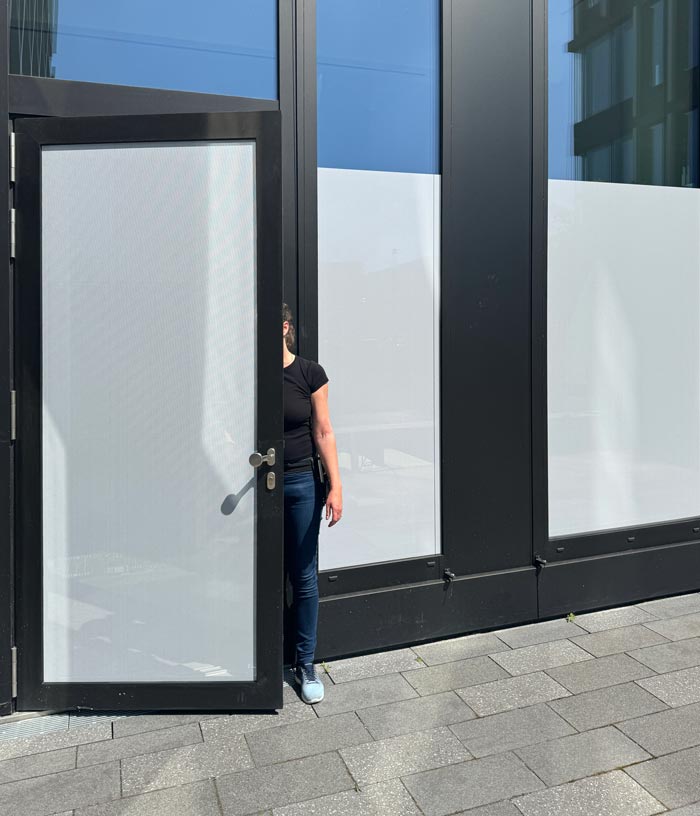 Die Fensterfront eines Familienzimmers wird 2m hoch mit Lochfolie als Sichtschutz beklebt.  Außenseitige Ansicht